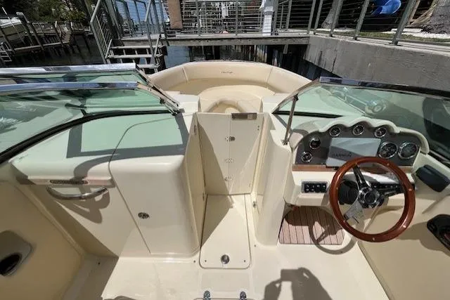 Slide: The Image of 2019 Chris-Craft Launch 27 boat docked near a waterfront home, showcasing sleek design. - 6