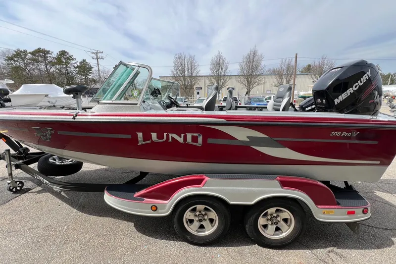 Slide: The Image of Red 2012 Lund 208 Pro-V GL boat on trailer, featuring Mercury outboard motor. - 2