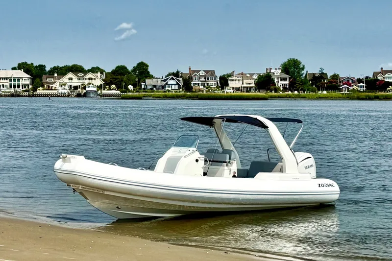 The Image of 2026 Zodiac Medline 7.5 boat on a sandy shore with waterfront homes in the background. - 0