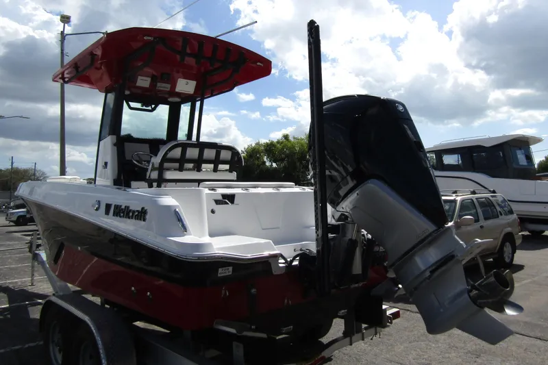 Slide: The Image of 2024 Wellcraft 223 Fisherman boat with outboard motor, parked on a trailer under cloudy sky. - 1
