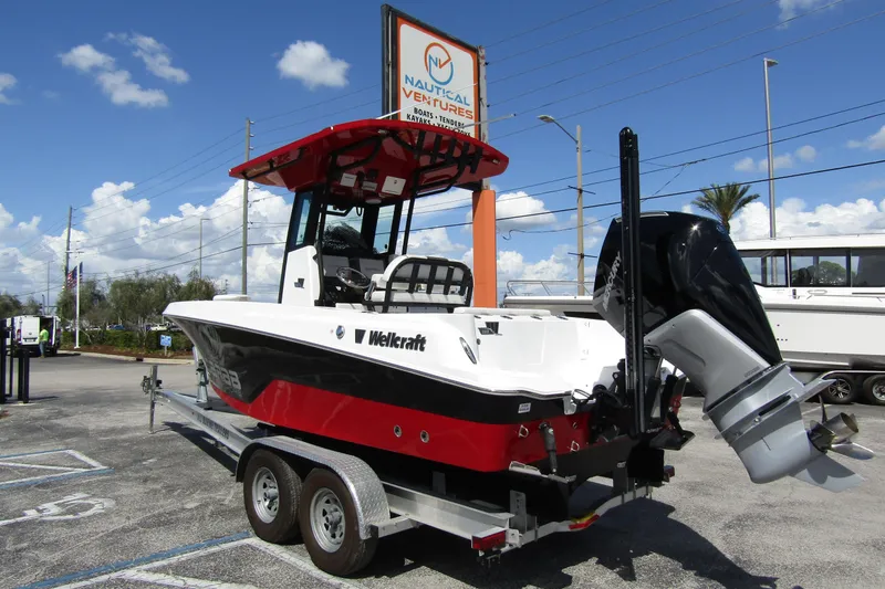 Slide: The Image of 2024 Wellcraft 223 Fisherman boat on trailer at dealership, under clear blue sky. - 2