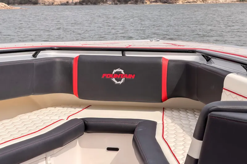 Slide: The Image of 2021 Fountain 38 SC boat interior with stylish seating and logo, overlooking a serene lake. - 14