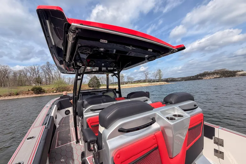 Slide: The Image of 2021 Fountain 38 SC boat interior with red and black seating on a scenic lake. - 34