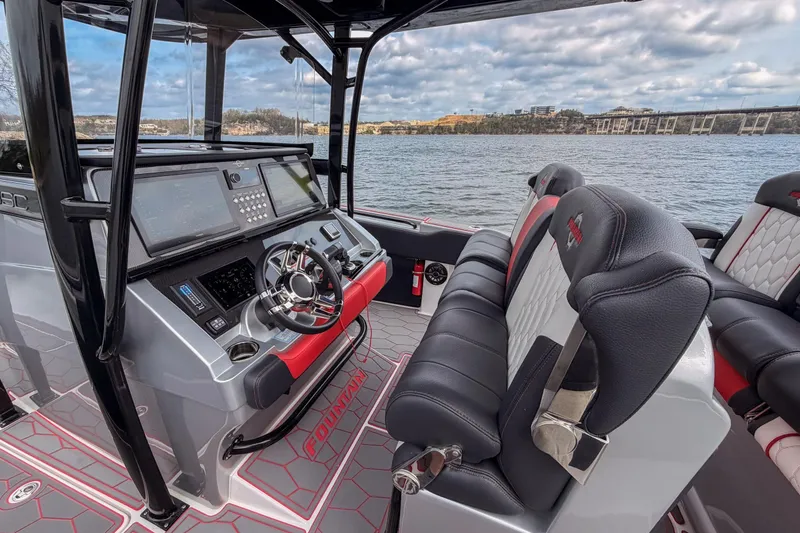 Slide: The Image of 2021 Fountain 38 SC boat interior with modern dashboard and luxurious seating on a scenic lake. - 37