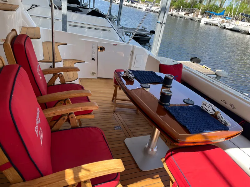 Slide: The Image of 2007 Sea Ray 58 Sedan Bridge yacht deck with red cushioned chairs and wooden table. - 11