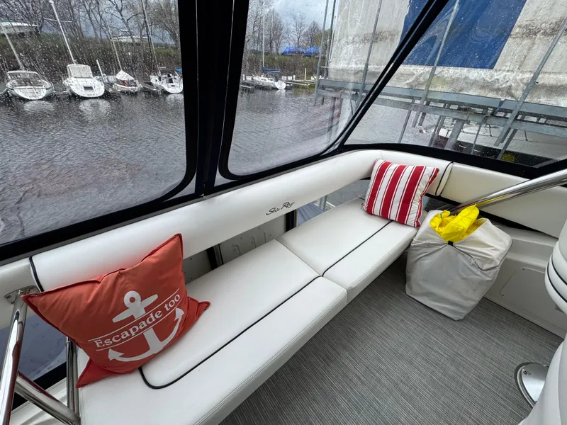 Slide: The Image of 2007 Sea Ray 58 Sedan Bridge interior with white seating, nautical pillows, and marina view. - 15
