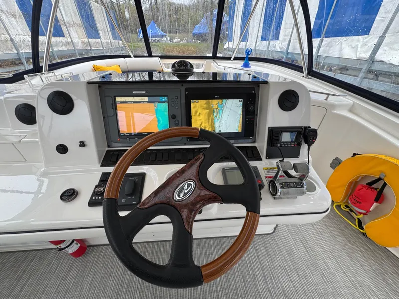 Slide: The Image of 2007 Sea Ray 58 Sedan Bridge helm with dual navigation screens and wooden steering wheel. - 21