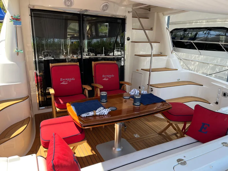 Slide: The Image of 2007 Sea Ray 58 Sedan Bridge yacht deck with red seating and wooden table. - 6