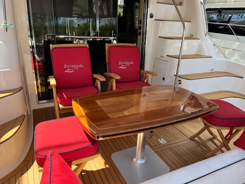 Slide: The Image of 2007 Sea Ray 58 Sedan Bridge yacht deck with red cushioned seating and wooden table. - 7