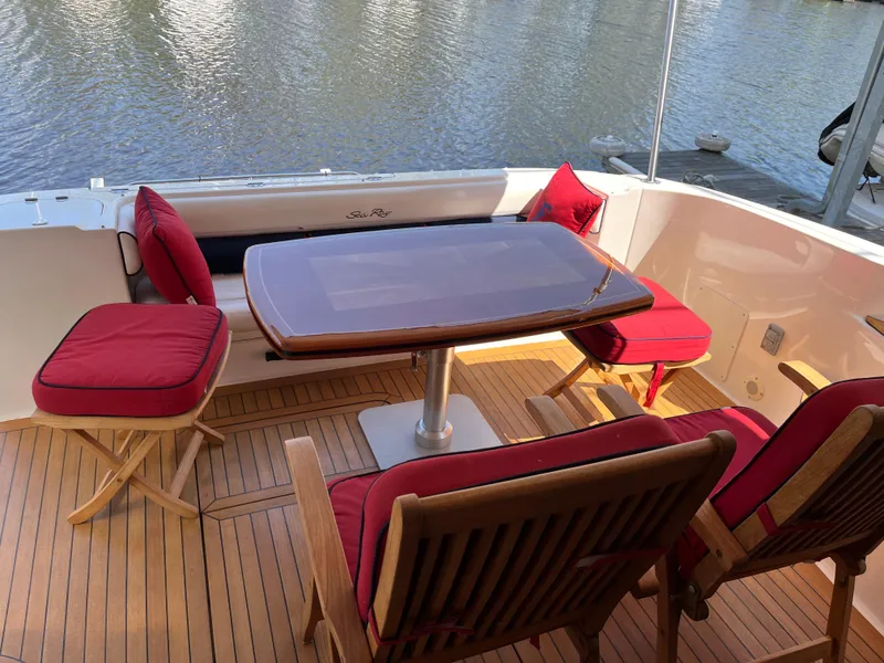 Slide: The Image of 2007 Sea Ray 58 Sedan Bridge yacht deck with red-cushioned seating and wooden table. - 9