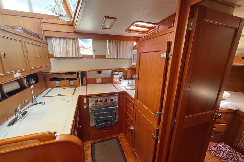 Slide: The Image of Interior of 1992 Grand Banks 46 Classic yacht, featuring a well-equipped wooden kitchen. - 28