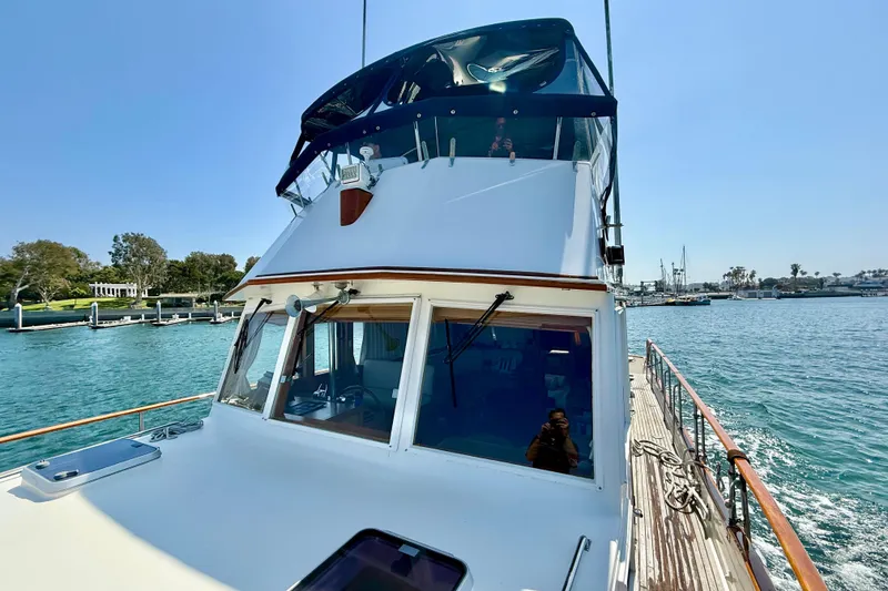 Slide: The Image of 1992 Grand Banks 46 Classic yacht on serene water, showcasing elegant design and spacious deck. - 52