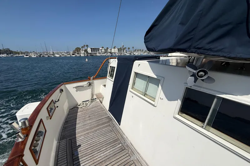 Slide: The Image of 1992 Grand Banks 46 Classic yacht deck with marina view, featuring wooden railings and windows. - 55