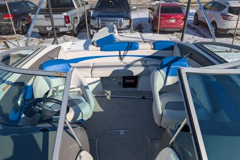 Slide: The Image of 2012 Rinker 216 Captiva Bowrider interior with blue and white seating, parked near vehicles. - 10
