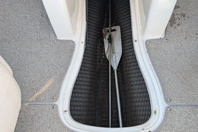 Slide: The Image of 2012 Rinker 216 Captiva Bowrider interior with paddle stored on textured flooring. - 9