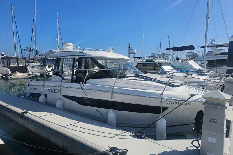 The Image of 2023 Jeanneau NC Weekender 895 docked at marina, clear blue sky background. - 0