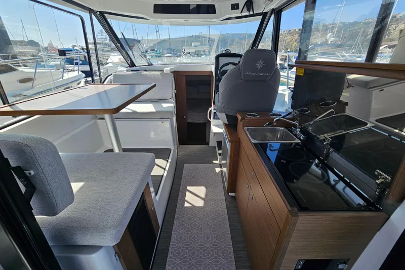 Slide: The Image of Interior of 2023 Jeanneau NC Weekender 895, featuring seating, table, and kitchenette. - 13