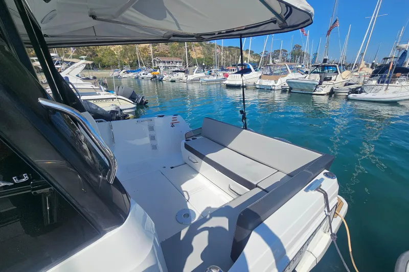 Slide: The Image of 2023 Jeanneau NC Weekender 895 docked in a marina, showcasing spacious deck seating. - 4