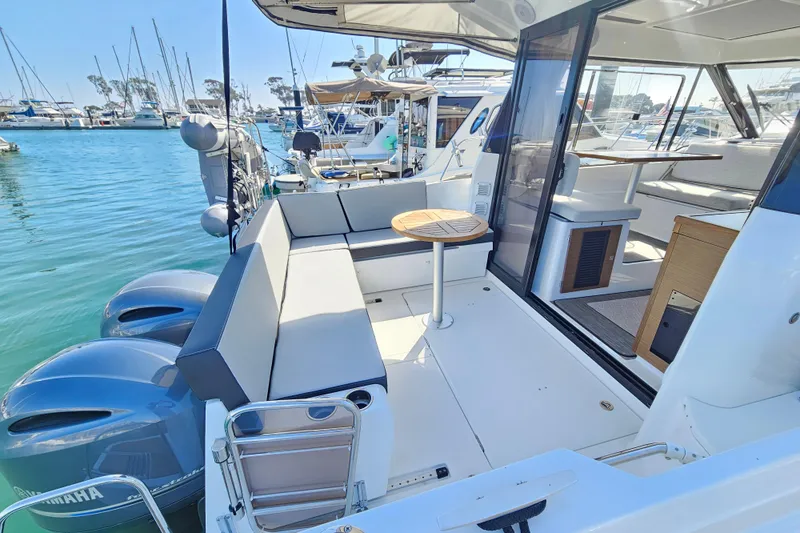 Slide: The Image of 2023 Jeanneau NC Weekender 895 boat interior with seating and table, docked at marina. - 5