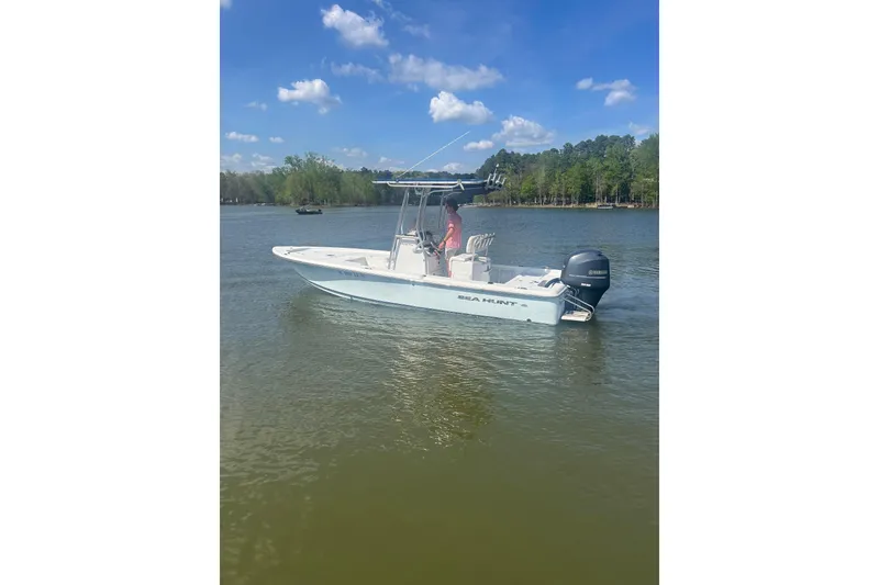 Slide: The Image of 2015 Sea Hunt BX 22 Pro boat on a calm lake under a clear blue sky. - 2