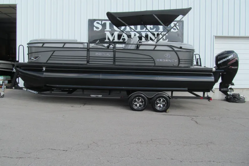 The Image of 2017 Regency 220 LE3 pontoon boat with Mercury outboard motor, parked on trailer. - 1