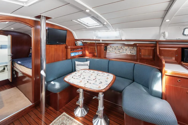 Slide: The Image of Interior of 2003 Beneteau 411 yacht, featuring elegant wood finishes and cozy seating area. - 10