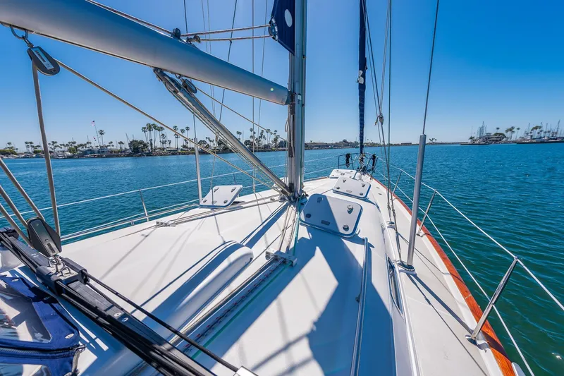 Slide: The Image of 2003 Beneteau 411 sailboat deck with polished railing and logo, docked by the water. - 23