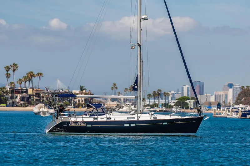 Slide: The Image of 2003 Beneteau 411 sailboat cruising in a marina with waterfront homes in the background. - 36