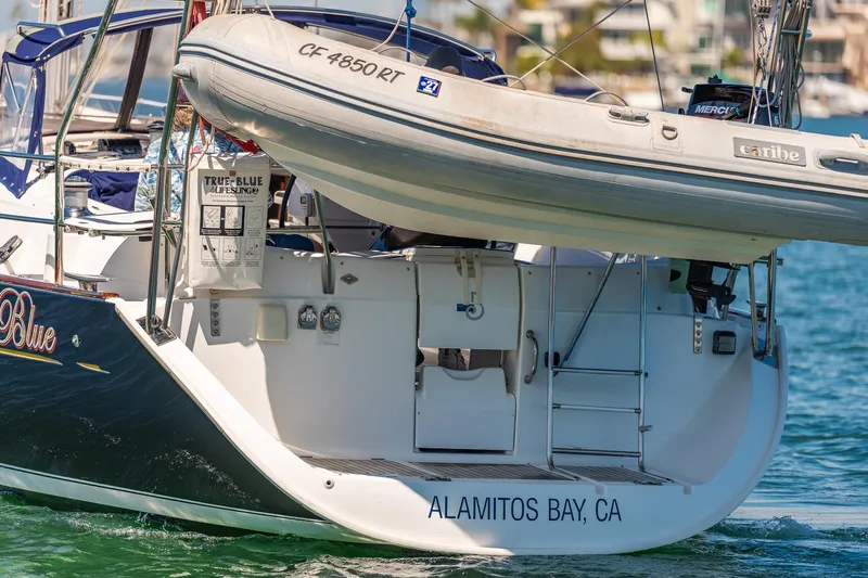 Slide: The Image of 2003 Beneteau 411 sailboat "True Blue" on water, featuring blue hull and cockpit canopy. - 40