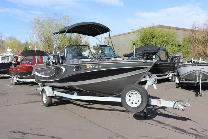 Slide: The Image of 2017 Lowe Fish & Ski 175 boat on trailer, parked outdoors with other boats. - 21