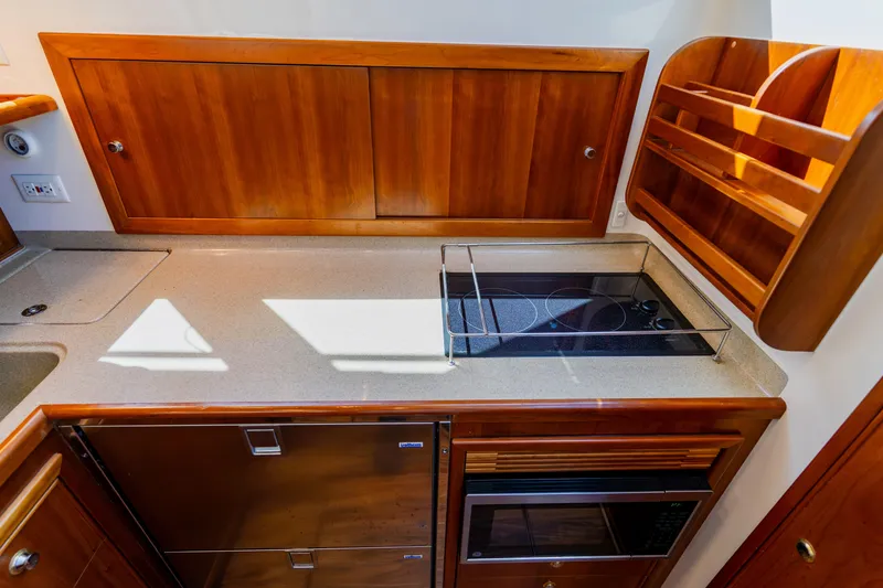 Slide: The Image of 2003 Wellcraft 400 Coastal yacht kitchen with stove, microwave, and wooden cabinetry. - 101