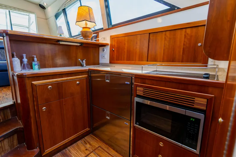 Slide: The Image of 2003 Wellcraft 400 Coastal yacht kitchen with wood cabinetry, microwave, and sink. - 102