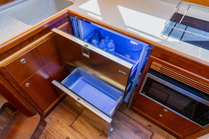 Slide: The Image of Wellcraft 400 Coastal 2003 yacht kitchen with open fridge, microwave, and wooden cabinetry. - 104