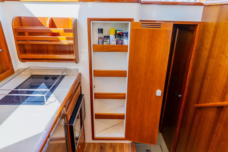 Slide: The Image of Wellcraft 400 Coastal 2003 yacht kitchen with stove, wooden cabinets, and open pantry shelves. - 108