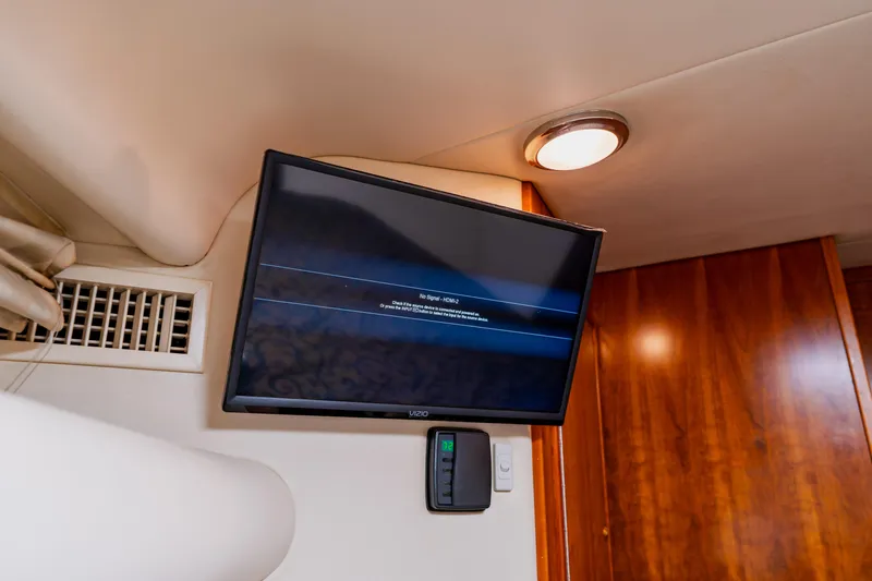 Slide: The Image of Wall-mounted TV in 2003 Wellcraft 400 Coastal yacht interior, with wooden paneling and ceiling light. - 113