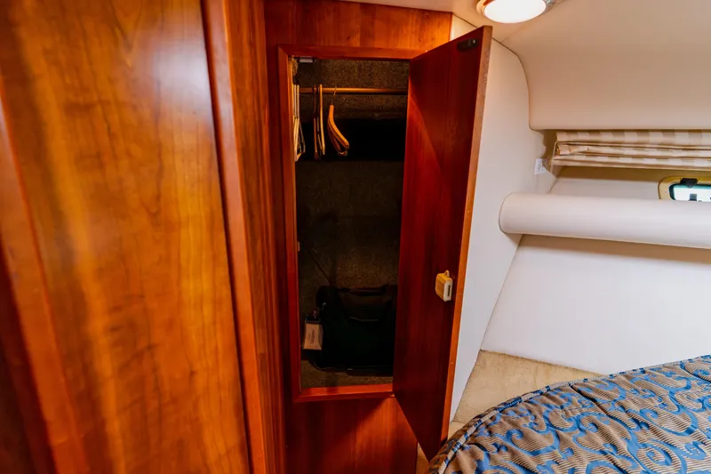 Slide: The Image of Wooden closet interior on 2003 Wellcraft 400 Coastal boat, featuring hangers and cozy cabin decor. - 114