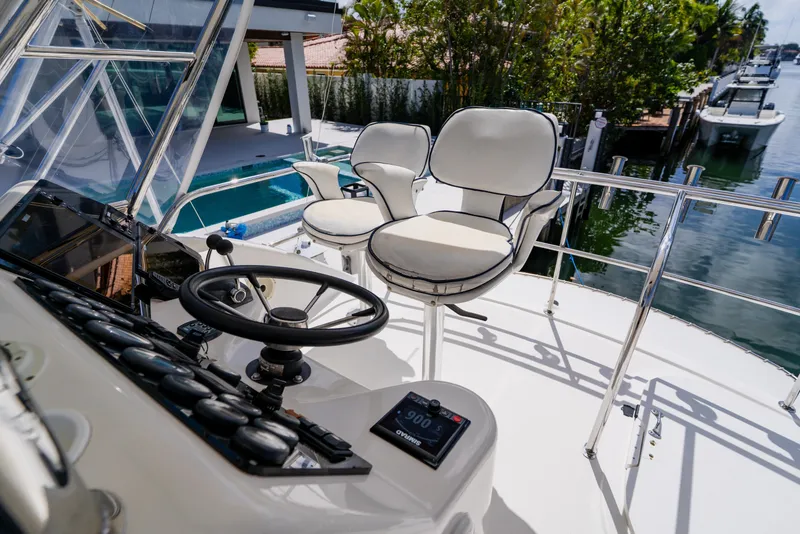 Slide: The Image of 2003 Wellcraft 400 Coastal yacht helm with steering wheel and cushioned seats by the water. - 51