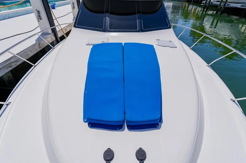 Slide: The Image of 2003 Wellcraft 400 Coastal boat deck with blue cushions, docked by clear water. - 76