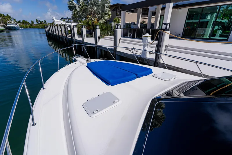 Slide: The Image of 2003 Wellcraft 400 Coastal yacht docked by waterfront property, featuring sleek design and blue cushions. - 77