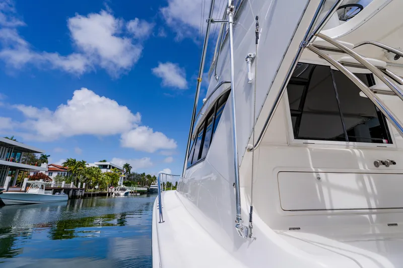 Slide: The Image of 2003 Wellcraft 400 Coastal yacht docked in a scenic waterfront area under a blue sky. - 85