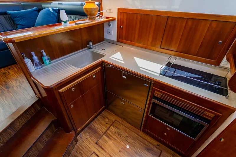 Slide: The Image of 2003 Wellcraft 400 Coastal yacht kitchen with wooden cabinetry, sink, stove, and microwave. - 99