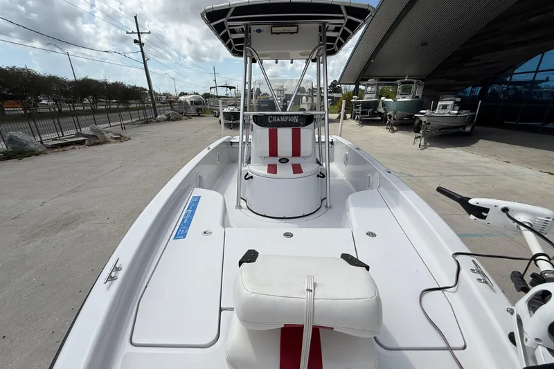 Slide: The Image of 2005 Champion 22 Bay Champ boat with white and red seating, docked outdoors. - 10