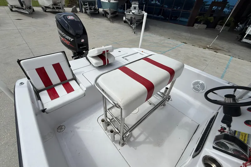 Slide: The Image of 2005 Champion 22 Bay Champ boat interior with red and white seating and Mercury engine. - 12