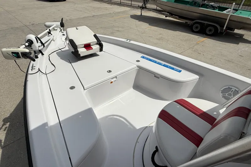 Slide: The Image of 2005 Champion 22 Bay Champ boat interior with white and red seating, docked outdoors. - 9