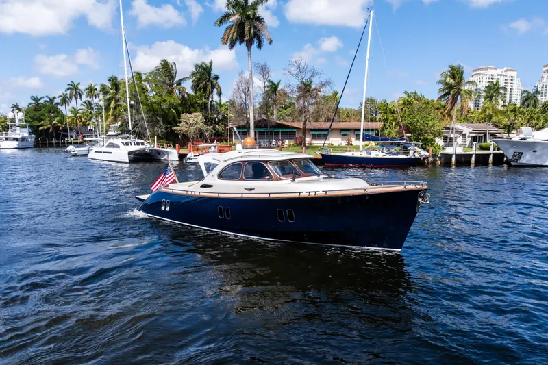 Slide: The Image of 2012 Zeelander 44 yacht cruising on a sunny day, surrounded by palm trees and other boats. - 2
