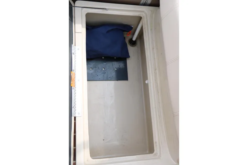 Slide: The Image of Storage compartment in 2014 Xcursion X23F boat, featuring a blue cushion and drainage pipe. - 26