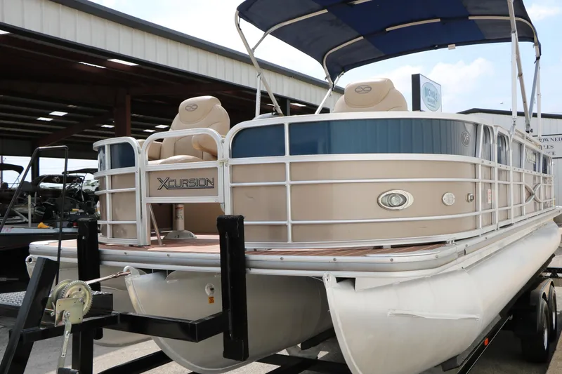 Slide: The Image of 2014 Xcursion X23F pontoon boat with canopy on trailer in storage facility. - 6