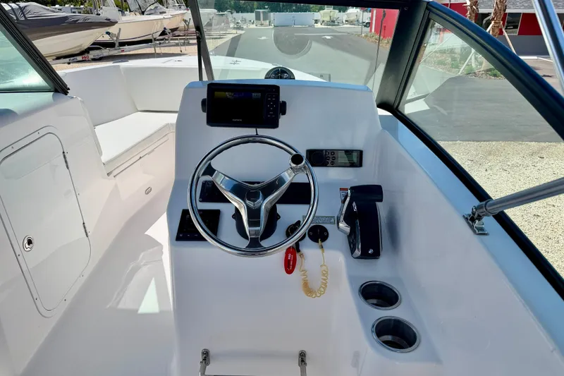 Slide: The Image of 2023 Aquasport 2200 Dual Console boat cockpit with steering wheel and controls. - 15