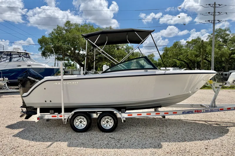 Slide: The Image of 2023 Aquasport 2200 Dual Console boat on trailer, under a clear blue sky. - 4