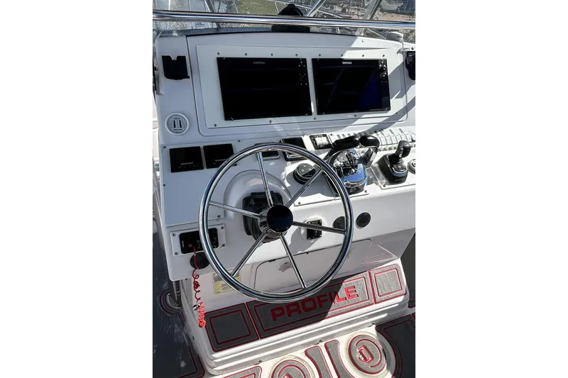 Slide: The Image of Control panel of a 2001 Pro-Line 3400 Bimini Cuddy boat with steering wheel and displays. - 14